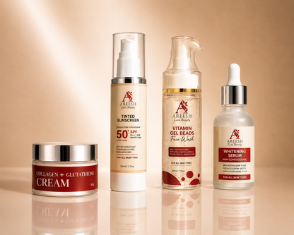Four skincare products from Alesha Beauty arranged on a reflective beige surface against a warm beige background: a Collagen + Glutamine Cream jar, a Tinted Sunscreen bottle, a Vitamin Gel Beads Face Wash bottle, and a Whitening Serum dropper bottle.